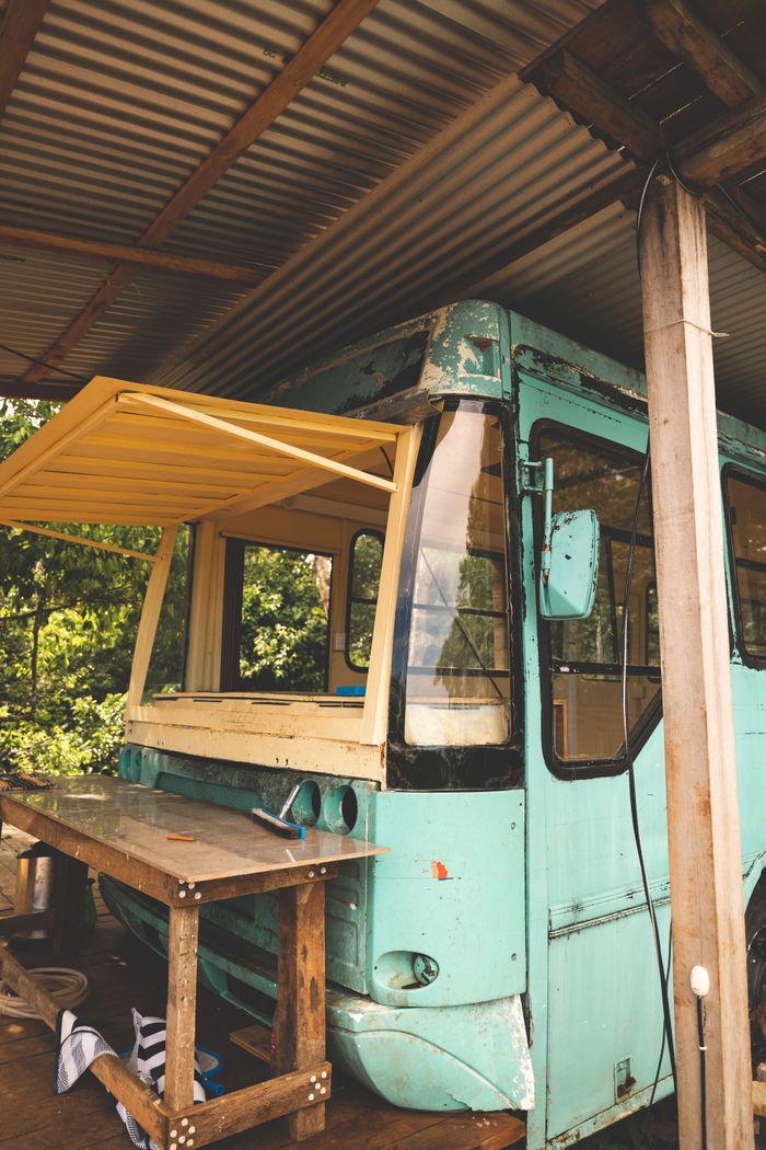 Vintage bus converted into an outdoor bar under a canopy, offering a rustic allure.